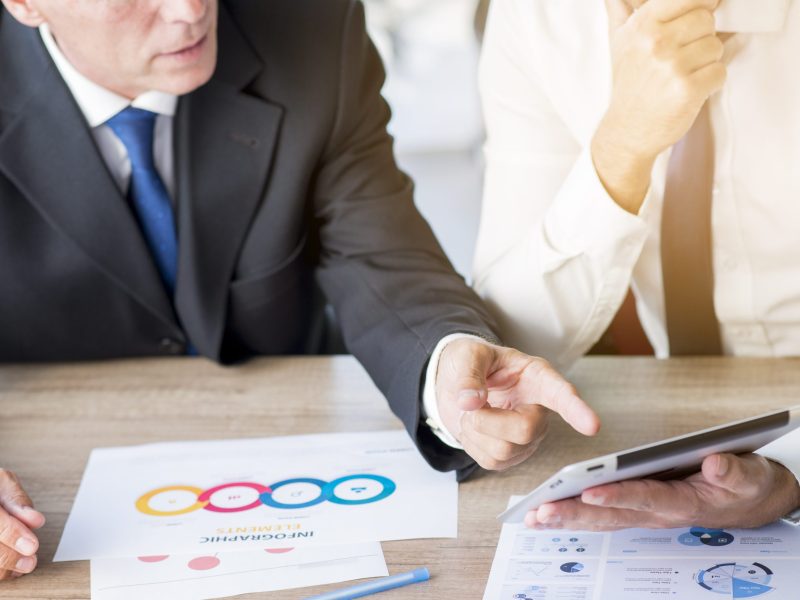 businessman-pointing-finger-digital-tablet-hold-by-his-partner-workplace businessman-pointing-finger-digital-tablet-hold-by-his-partner-workplace